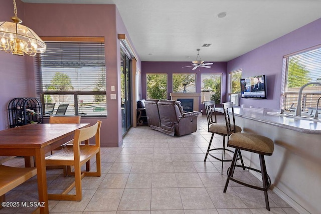 tiled dining space featuring sink, plenty of natural light, and ceiling fan with notable chandelier