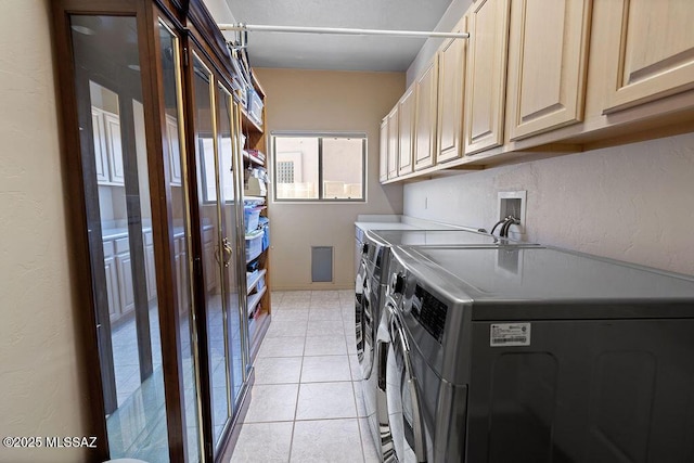 washroom with washer and clothes dryer, light tile patterned floors, and cabinets