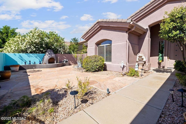 view of side of property featuring exterior fireplace and a patio area