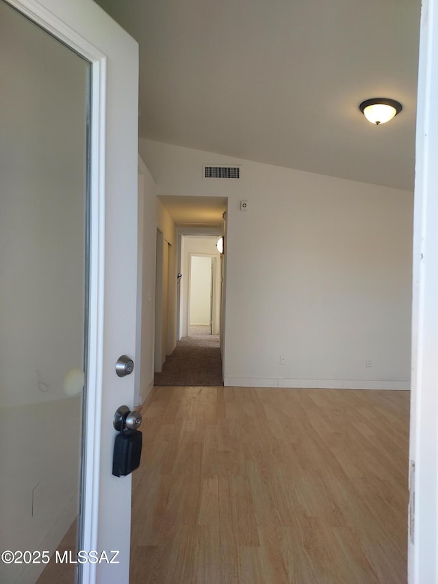 hall featuring light hardwood / wood-style floors and vaulted ceiling