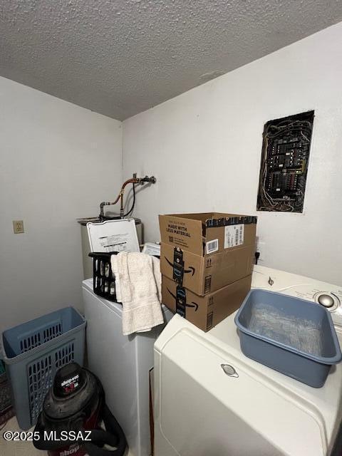 washroom featuring water heater, independent washer and dryer, and a textured ceiling