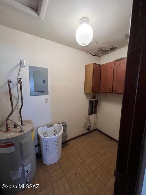 laundry room with water heater, electric panel, and cabinets