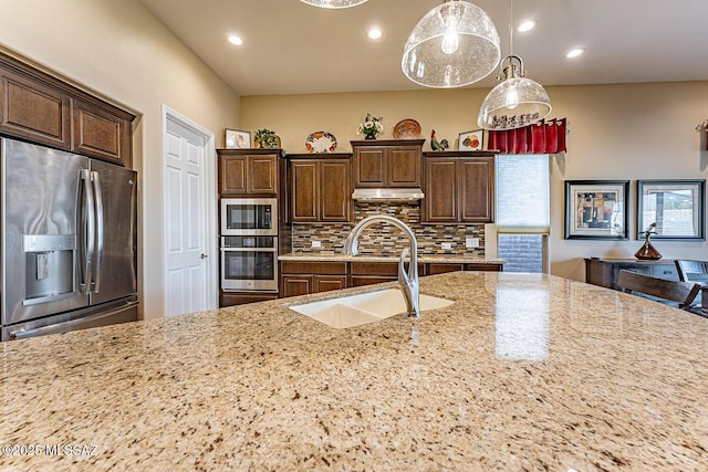 kitchen with appliances with stainless steel finishes, decorative backsplash, sink, and light stone countertops