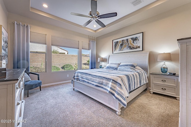 bedroom featuring light carpet, ceiling fan, and a tray ceiling