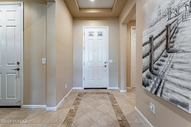 foyer featuring light tile patterned flooring and a tray ceiling