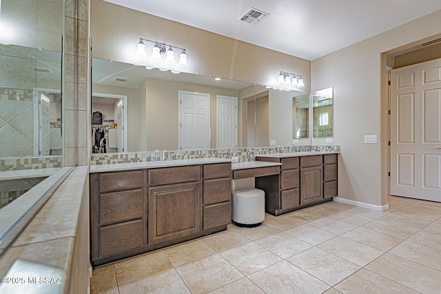 bathroom featuring tasteful backsplash, vanity, a tile shower, and tile patterned flooring