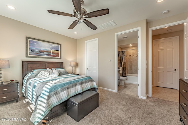 bedroom featuring ceiling fan, light colored carpet, and ensuite bath