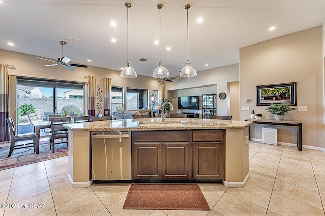 kitchen featuring a center island with sink, sink, pendant lighting, stainless steel dishwasher, and light stone countertops