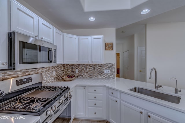 kitchen with backsplash, white cabinets, stainless steel appliances, and a sink