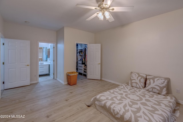 bedroom with a spacious closet, baseboards, and light wood finished floors