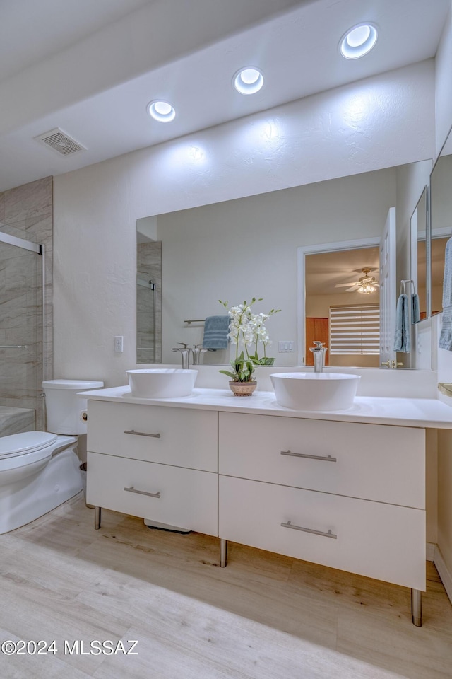 bathroom featuring double vanity, toilet, tiled shower, and a sink