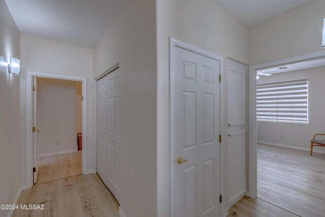 hallway featuring light wood-style flooring and baseboards