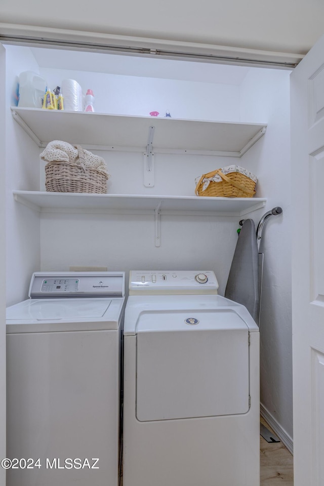 clothes washing area featuring light wood finished floors, laundry area, baseboards, and separate washer and dryer