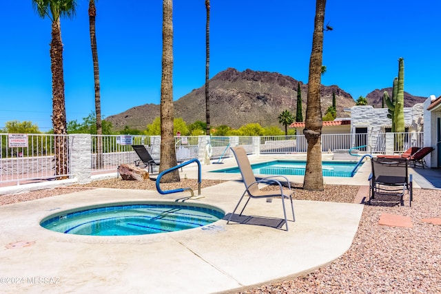 pool featuring a mountain view, a hot tub, and fence