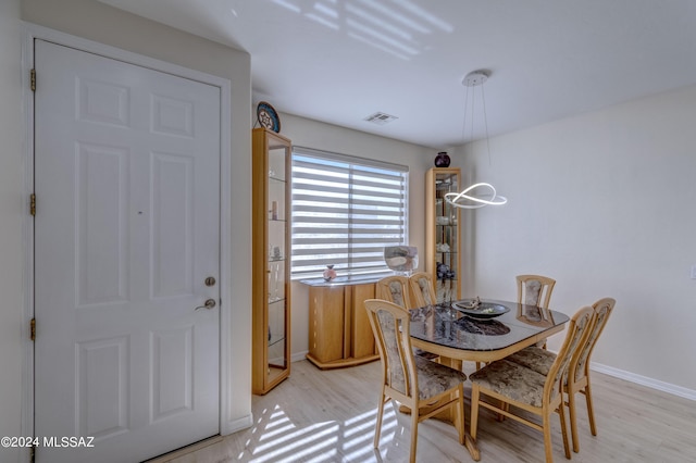 dining room with light wood-type flooring, visible vents, and baseboards