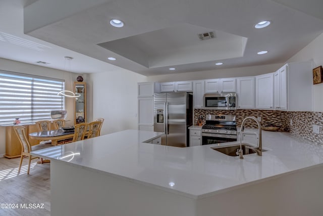 kitchen with visible vents, a sink, decorative backsplash, stainless steel appliances, and a raised ceiling