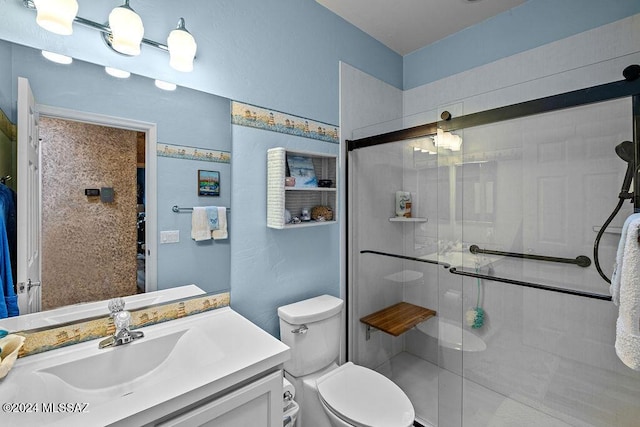 bathroom featuring vanity, toilet, and a shower with shower door