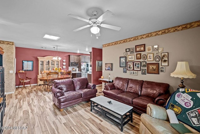 living room featuring light hardwood / wood-style flooring and ceiling fan with notable chandelier