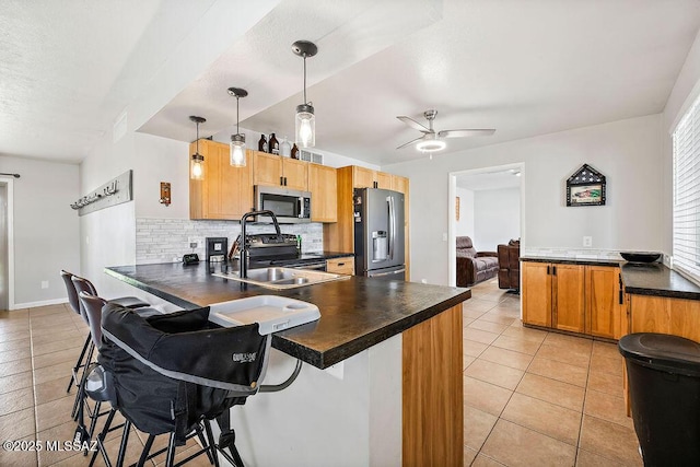 kitchen with a kitchen breakfast bar, appliances with stainless steel finishes, kitchen peninsula, decorative light fixtures, and backsplash