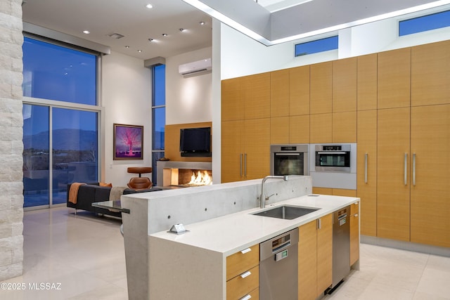 kitchen featuring a large island, a wall unit AC, appliances with stainless steel finishes, a towering ceiling, and sink