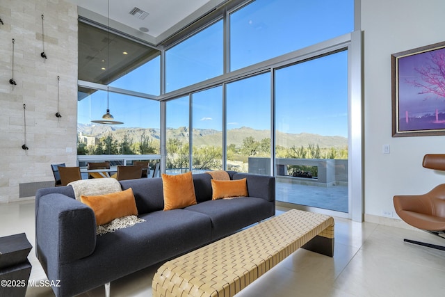 living room featuring expansive windows, a high ceiling, plenty of natural light, and a mountain view