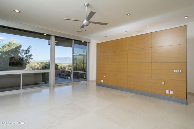 unfurnished room featuring ceiling fan, light tile patterned floors, a mountain view, and expansive windows