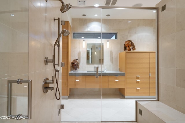 bathroom with a shower with shower door, vanity, and tile walls