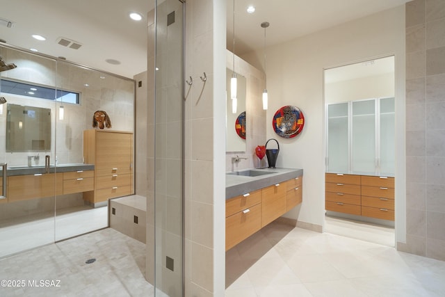 bathroom with an enclosed shower, vanity, tile walls, and tile patterned floors