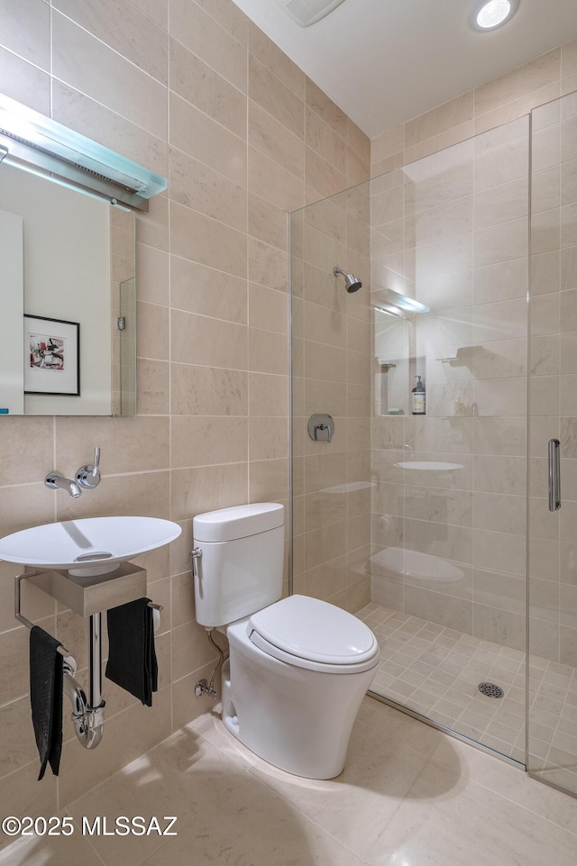 bathroom with toilet, a shower with door, tasteful backsplash, tile walls, and tile patterned floors