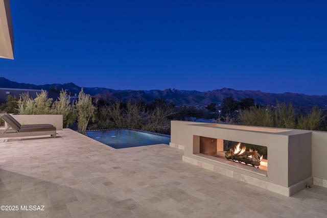 view of pool with a mountain view, a patio area, and exterior fireplace