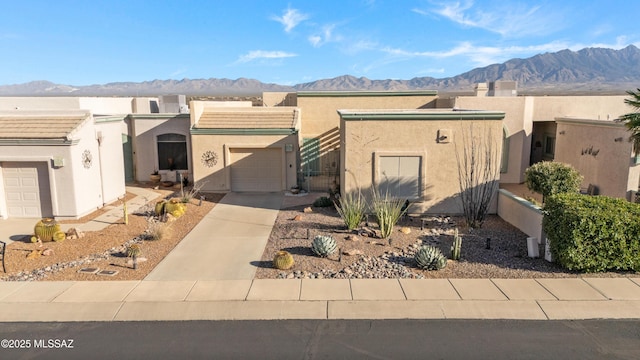 pueblo-style home featuring a garage and a mountain view