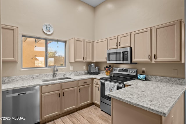 kitchen featuring light brown cabinetry, appliances with stainless steel finishes, light hardwood / wood-style flooring, and sink