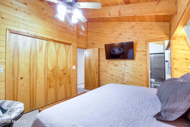 carpeted bedroom with ceiling fan, connected bathroom, wood walls, and beamed ceiling