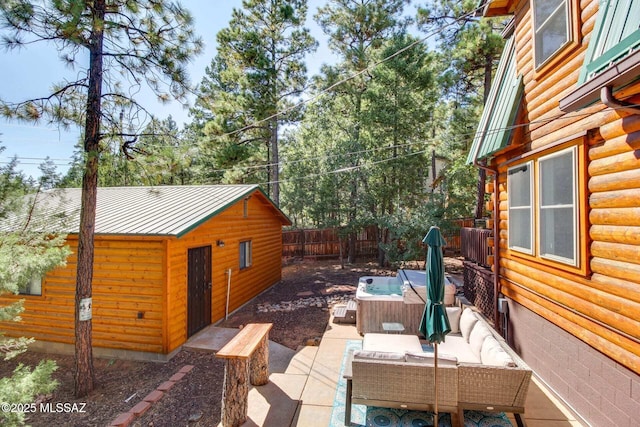 view of patio / terrace featuring outdoor lounge area, a hot tub, and an outdoor structure