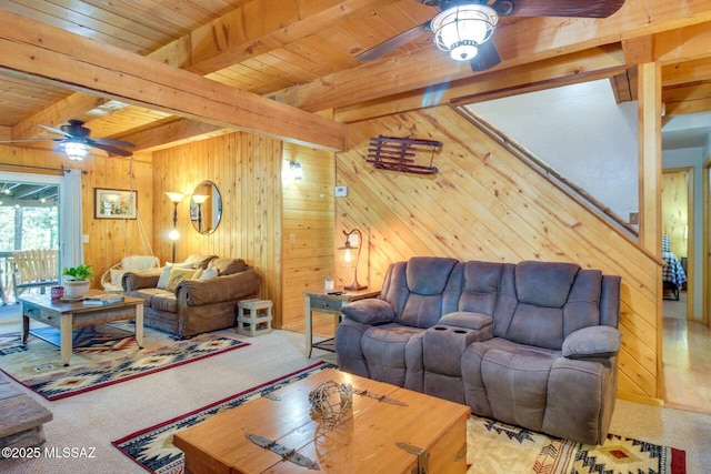 carpeted living room with ceiling fan, wood ceiling, wooden walls, and beamed ceiling