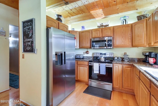 kitchen with wood ceiling, appliances with stainless steel finishes, dark stone countertops, beam ceiling, and light hardwood / wood-style flooring