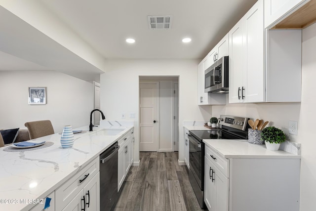 kitchen with a kitchen breakfast bar, white cabinetry, light stone counters, and appliances with stainless steel finishes