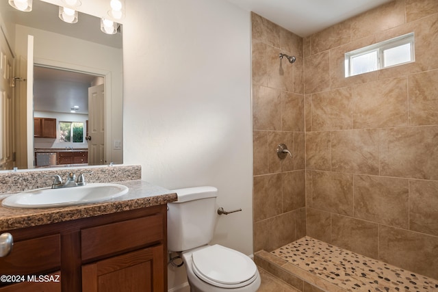 bathroom featuring toilet, tiled shower, and vanity