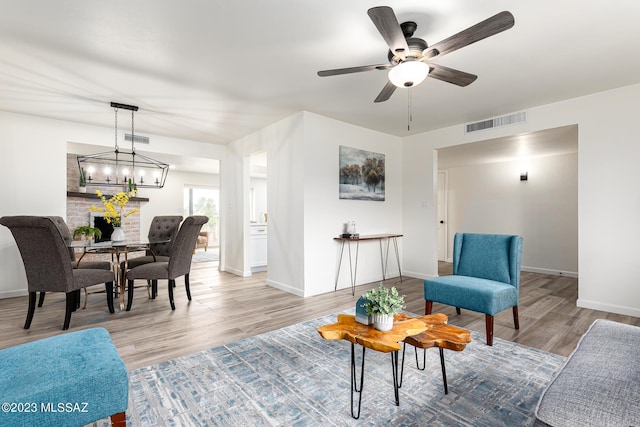 living room with light hardwood / wood-style floors and ceiling fan with notable chandelier