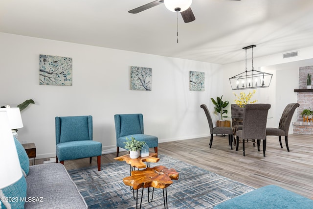 living room featuring ceiling fan with notable chandelier and hardwood / wood-style flooring