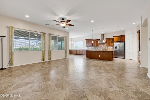 kitchen with pendant lighting, decorative backsplash, a center island, stainless steel fridge with ice dispenser, and wall chimney exhaust hood