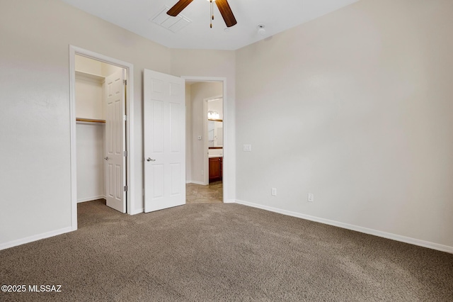 unfurnished bedroom with a spacious closet, a closet, ceiling fan, and carpet flooring