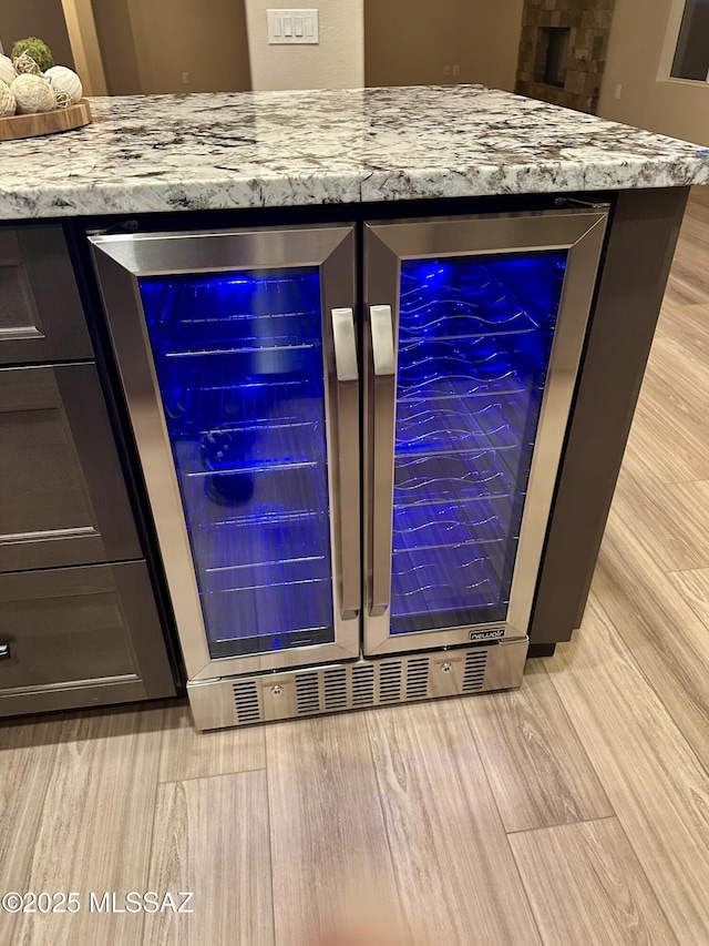 room details with beverage cooler, a bar, and wood finished floors