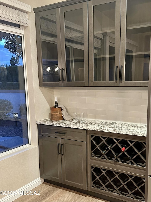 bar featuring light wood finished floors and tasteful backsplash