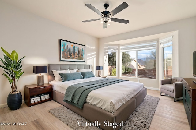 bedroom with a ceiling fan, baseboards, and light wood finished floors