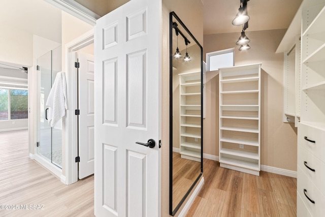 walk in closet featuring vaulted ceiling and light hardwood / wood-style flooring