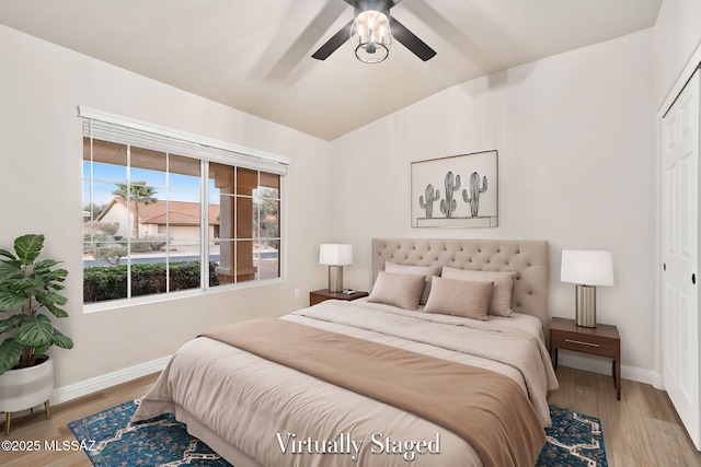 bedroom featuring light wood-type flooring, a closet, lofted ceiling, and baseboards