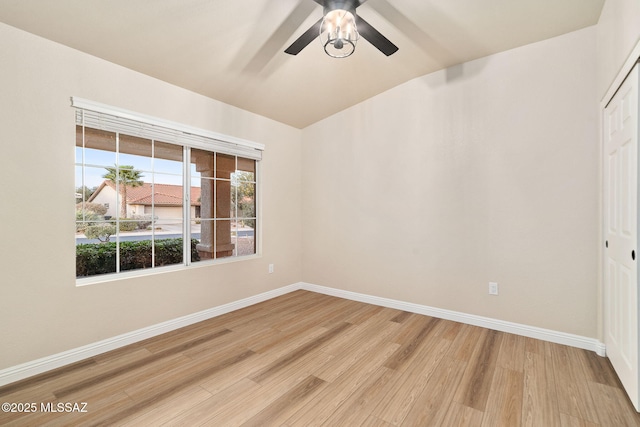 empty room with ceiling fan, baseboards, vaulted ceiling, and wood finished floors