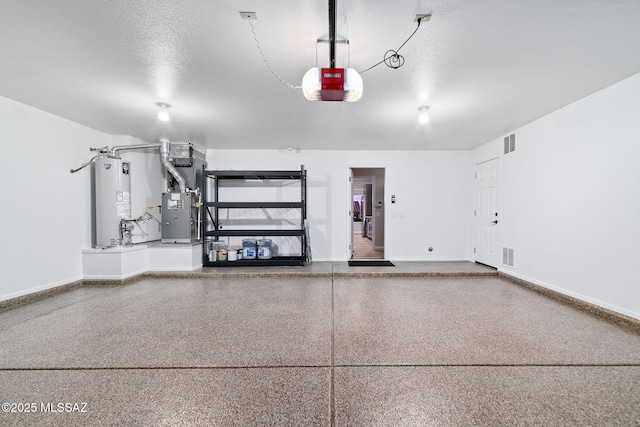 garage featuring water heater, heating unit, visible vents, and a garage door opener