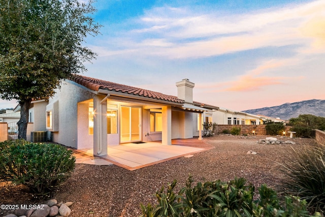 rear view of house with fence, central air condition unit, a patio area, a mountain view, and stucco siding